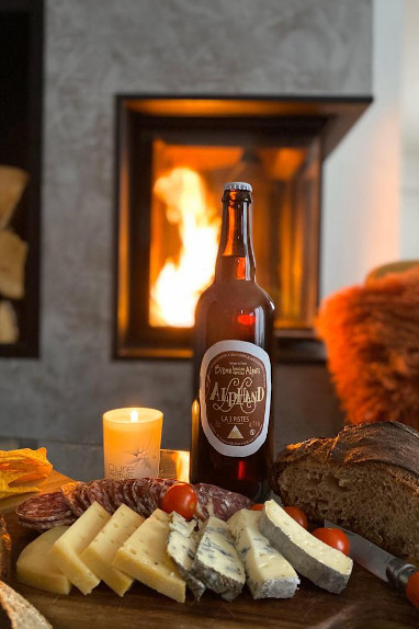 Bouteille de bière artisanale Alphand devant un plateau de fromage et de charcuterie