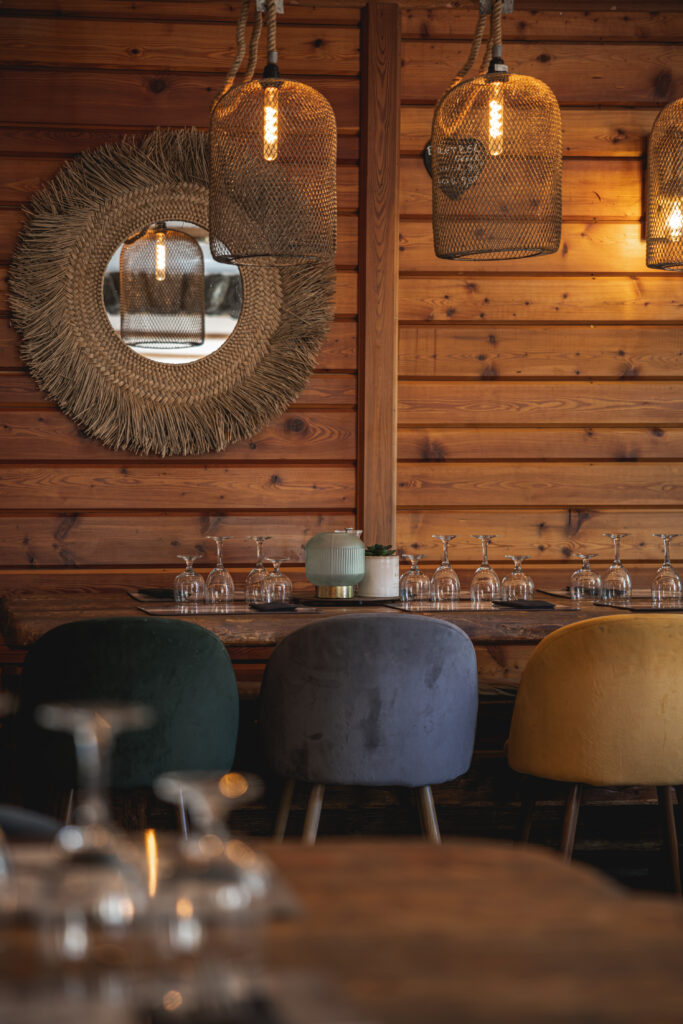 La salle du restaurant Alphand, très cosy avec son mur de fond en bois des luminaires en en matières naturelles et ses fauteuilles en velours, restaurant de montagne situé à Vallouise dans les Hautes-Allpes